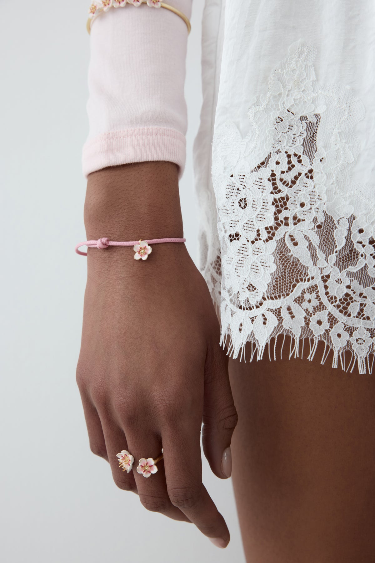 Pink thread bracelet with a tiny white cherry blossom